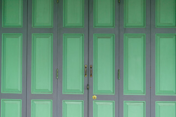 Closeup detailed texture of Green paint peeling off of an old wooden door.