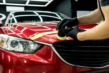 Obraz na płótnie Canvas Car service worker polishes a car details with orbital polisher.