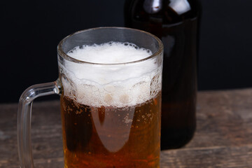 Glass of beer and beer bottle on a wooden table closr-up
