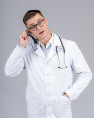 Young handsome doctor in scrubs put phonendoscope to ear. Funny emotions.