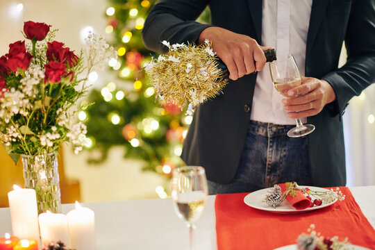 Cropped image of young man pouring glass of champagne at Christmas party