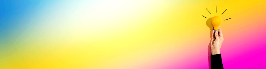 Person holding a yellow light bulb - Idea and creativity theme