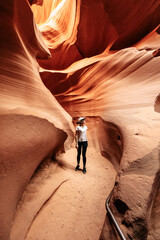 A young woman is walking on path between bizarre rocks in incredible Antelope Canyon, Arizona, USA.
