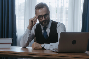 Businessman thinking and looking laptop at office.