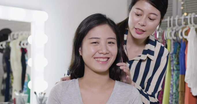 slow motion smiling asian famous lady celebrity looking in camera as mirror while female stylist showing her new hairstyle.