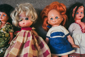 a group of four old children's dolls in old dresses. A symbol of the communist industry. The concept of old children's toys