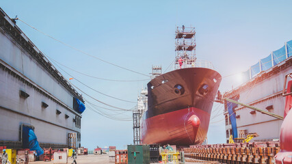 Shipyard Oil Tanker ship Moored in floating dry dock for maintenance, Shiprepair, after sandblasting and painting with scaffolding on board, Low angle view of front ship - obrazy, fototapety, plakaty