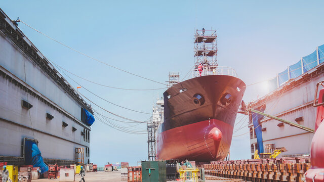 Shipyard Oil Tanker ship Moored in floating dry dock for maintenance, Shiprepair, after sandblasting and painting with scaffolding on board, Low angle view of front ship