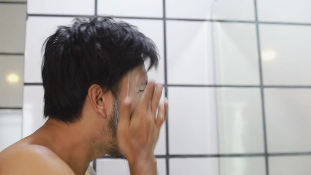 Young asian man use foam to wash your face after showering.