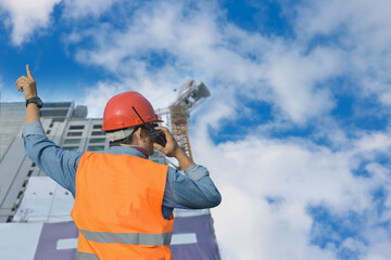 Male worker at construction site with hand holding walkie-talkie operation work by pointing hand...