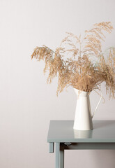 Pampas grass in vase on a coffee table against a gray wall. Seasonal home decoration. Cozy stylish home. vertical image