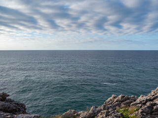 Cliffs by the sea under a blue cloudy sky