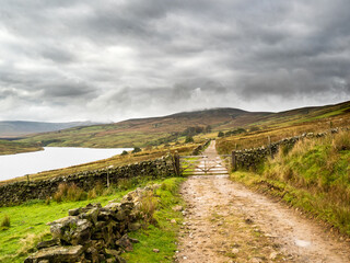 Fototapeta na wymiar A country track winds its way through moorland around Scar House reservoir. Nidderdale. Yorkshire Dales