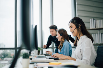 Side view of woman call center with headsets using computers in the office.