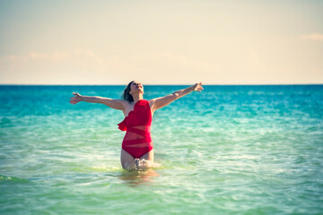A young slender, beautiful European middle-aged woman is swimming in the sea, a mature brunette in a red bathing suit is enjoying her summer vacation. Freedom and cheerfulness concept