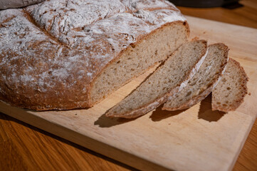 fresh farmhouse bread lies wrapped in a cloth on a wooden board and was cut into slices