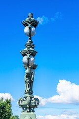 Fototapeta na wymiar Russia, St. Petersburg, July 2020. Fragment of a vintage lantern in Art Nouveau style against the blue sky.