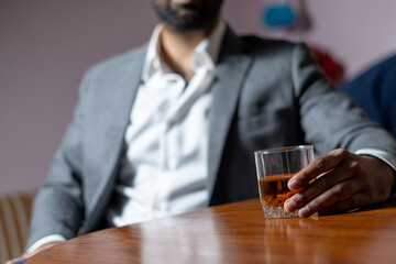 wine glass in hand businessman wearing white shirt grey suit  dark and moody environment
