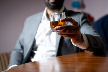 wine glass in hand businessman wearing white shirt grey suit  dark and moody environment