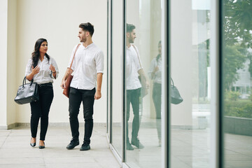 Young serious business people walking in office corridor and discussing project development