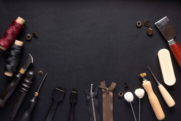 set of different tools for making leather goods on black leather background. Manual sewing of the product. place for your text or design. top view