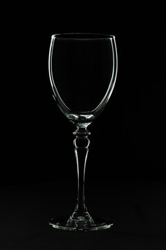 Low key studio image of a wine glass with a black background. The silhouette of the glass is lightning up due to flash light