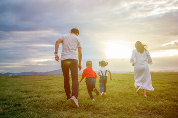 Asian family walking and running on the Meadow at sunset with happy emotion. Family, Holiday and Travel concept.