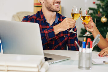 Smiling software developer drinking champagne with colleague after finishing big project on Christmas eve