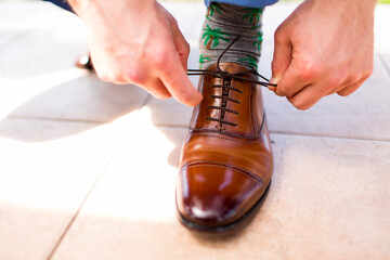 close up of Man tying nice brown dress shoe with palm tree socks