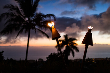 Tiki torches close up with ocean sunset view in the background palm trees silohuette gorgeous