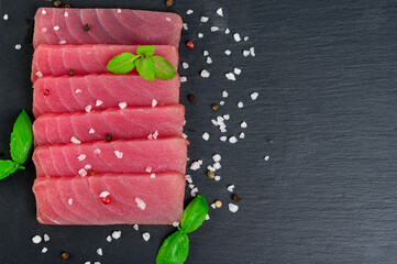 Fresh raw tuna steak with basil. On black rustic background