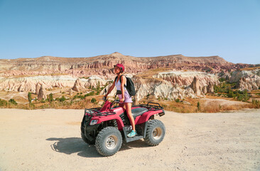 Young woman riding red quad bike at the desert valley in Cappadocia Turkey 2020. Red atv quad at the valley.