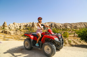 Young woman riding red quad bike at the desert valley in Cappadocia Turkey 2020. Red atv quad at the valley. © Maria Kasimova