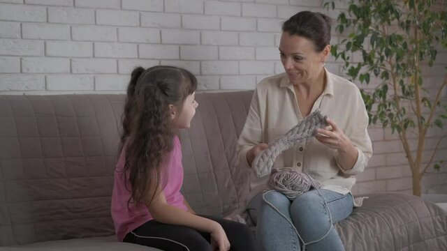 Knit with family. A mother show her knitted socks to her daughter and learn her daughter to make handmade clothes.
