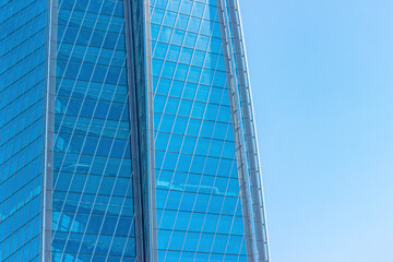 sky and exterior glass walls of a modern Corporate building. Business offices of skyscraper on blue sky background.