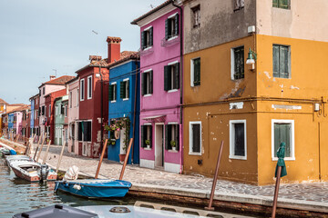 Colored houses on Burano island and canal with boats in the venetian lagoon