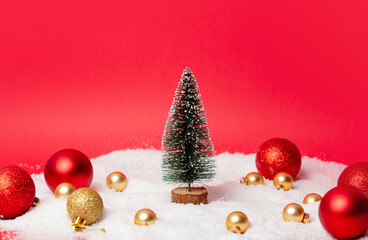 Christmas tree with baubles and snow around on red background
