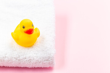 One rubber duck on white terry bath towel, pink background with place for copy space, horizontal