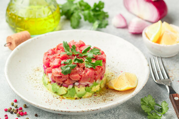 Tuna tartare tartar with avocado and purple onion. Served with cilantro (coriander), lemon and freshly ground pepper. Delicious appetizer (salad) of raw fresh fish. Selective focus - 386195875