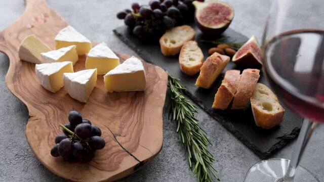 Camembert or brie cheese with glass of red wine, grapes, baguette and figs. Cheese platter, appetizer snack table