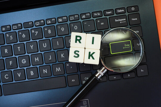 Text on risk on cubes with a magnifying glass on the laptop keyboard 