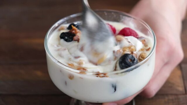 Eating cream yogurt dessert with granola and berries. Healthy yogurt parfait