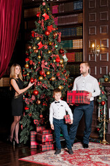 Fototapeta na wymiar happy young family with one child holding christmas gift and smiling at camera.happy family mother father and baby at christmas tree at home