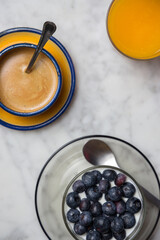 Healthy breakfast with muesli, yogurt and fruit, coffee cup and orange juice