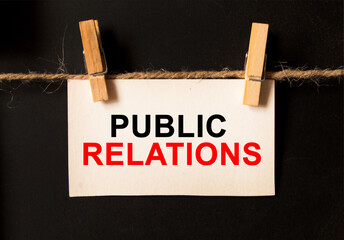 a sheet on a black background with text PUBLIC RELATIONS. business concept