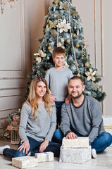 Obraz na płótnie Canvas happy young family with one child holding christmas gift and smiling at camera.happy family mother father and baby at christmas tree at home