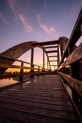 wooden bridge over lake in a sunset