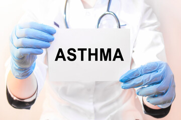 The doctor's blue - gloved hands show the word ASTHMA - . a gloved hand on a white background. Medical concept. the medicine