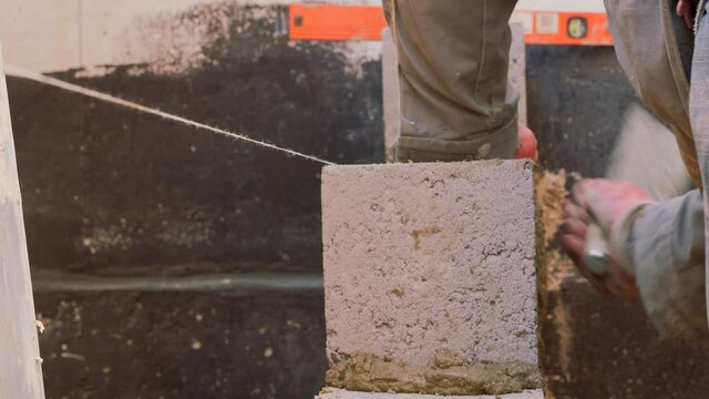 Construction work. Cinder block laying. Work of masons. Leveling the level of brickwork with a special tool. Clogging of seams with a solution. Distribution of mortar.