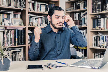 Young entrepreneur working from home, talking on his cell phone.